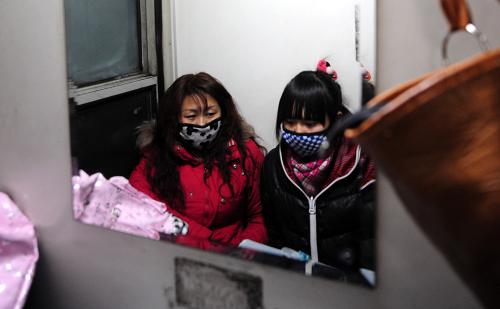 在包頭開(kāi)往南昌的1484次列車上,兩名旅客坐在洗漱間休息(攝于1月27日)。新華社記者 任軍川 攝