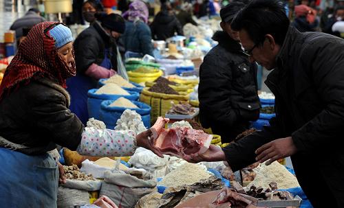 2月4日,西藏墨竹工卡縣的農(nóng)民次仁(左)在拉薩沖賽康市場出售自家養(yǎng)殖的藏豬肉。新華社記者 格桑達瓦 攝