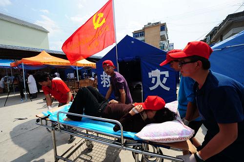 3月11日,中學生志愿者在幫助運送病人。云南盈江地震發(fā)生后,該省各級黨委政府反應迅速,安排部署各項救災工作,把救治傷員的任務放在重中之重。截至11日下午,盈江縣人民醫(yī)院共收治傷病員220余人,其中160余名重傷者轉往騰沖等地救治。醫(yī)院的球場目前被開辟成為臨時救助中心,病人得到有效救治。新華社記者 秦晴 攝