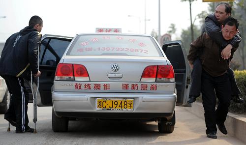 3月30日,湖南省公安廳交警總隊機動車駕駛?cè)丝荚囍行目颇咳嫣犊紙龅缆飞?,考生李兆湘在教練的幫助下?zhǔn)備進(jìn)入考試車輛,另一位考生(左)剛剛結(jié)束考試。新華社記者 李尕 攝
