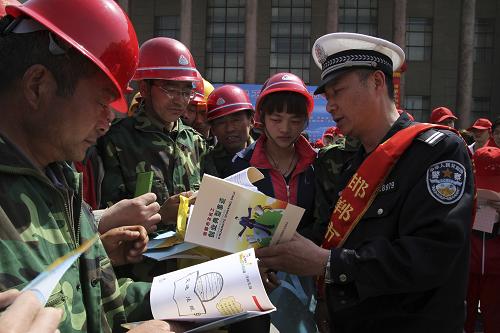 4月19日,在啟動(dòng)儀式現(xiàn)場(chǎng),一名交警志愿者(右一)向農(nóng)民工代表發(fā)放宣傳資料。新華社發(fā)(王九忠 攝)