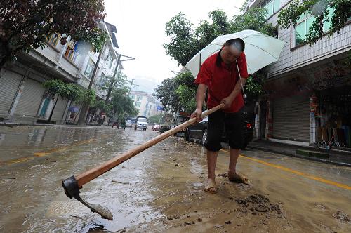 6月7日,一位當(dāng)?shù)厝罕娫谇謇硗兛h城街道上的淤泥。在貴州省望謨縣遭受暴雨洪災(zāi)的第二天,洪水退去后留下了大量泥沙、樹(shù)枝等雜物,縣城部分地段還出現(xiàn)內(nèi)澇。當(dāng)?shù)亟M織消防、武警、民兵預(yù)備役等330多人,6日已趕到縣城,連夜全力清淤,確保高考順利進(jìn)行。截至7日4時(shí),此次洪澇災(zāi)害已經(jīng)造成望謨縣14人死亡,35人失蹤。新華社記者 劉續(xù) 攝