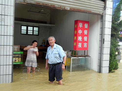6月10日,江西修水縣一家飯店的店主站在齊膝的洪水中。新華社發(fā)