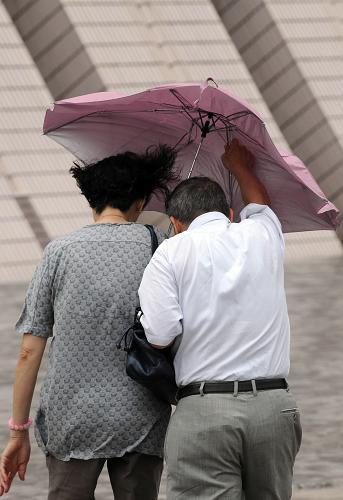 6月22日,兩位香港市民頂著風(fēng)雨出行。新華社記者 宋振平 攝