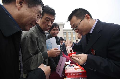 11月6日,天津市煙草專賣局的工作人員(右)在銷毀現(xiàn)場為市民講解如何識別假冒香煙。新華社發(fā)(李方宇 攝)