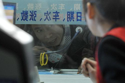 1月1日,在杭州汽車東站火車票大賣場購票的旅客手持身份證在窗口前咨詢。新華社記者 黃宗治 攝