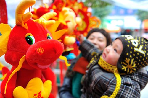 1月18日,在湖北襄陽保康縣城,一對母子在選購“龍”形象的新年飾品。新華社發(fā)(楊韜 攝)