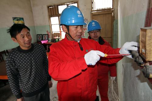 1月24日,長興煤山供電營業(yè)所員工李基新(右)在東川村村民張建華家中排除用電故障。新華社記者 徐昱 攝