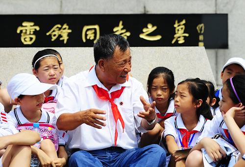 2009年7月29日,雷鋒生前戰(zhàn)友喬安山(中)在坐落在撫順市的雷鋒紀(jì)念館雷鋒墓前向天津南開(kāi)區(qū)中營(yíng)小學(xué)的“學(xué)雷鋒小標(biāo)兵”講述雷鋒生前的先進(jìn)事跡。 新華社發(fā)