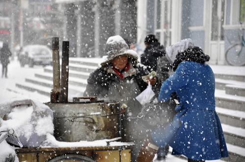 3月30日,在呼倫貝爾牙克石市,一名商販在風(fēng)雪中售賣(mài)烤紅薯。新華社發(fā)(余昌軍 攝)