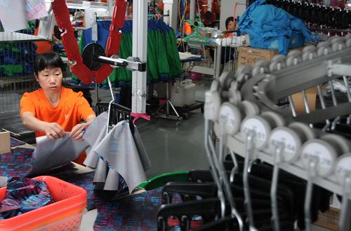 工人在福建省晉江市某著名體育品牌服裝生產(chǎn)流水線上作業(yè)(5月23日攝)。新華社記者 林善傳 攝