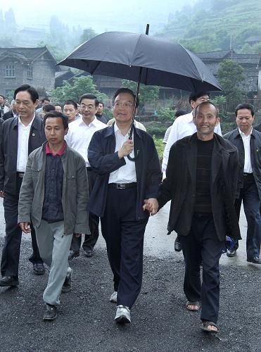 這是5月25日,在武陵山深處的古丈縣雙溪鄉(xiāng)梳頭溪村,溫家寶打著雨傘與村民彭武坤手拉手邊走邊談。新華社記者 龐興雷 攝