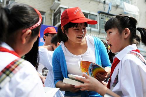 5月27日,合肥工業(yè)大學(xué)的志愿者(中)向流動兒童捐贈書籍。新華社記者 杜宇 攝