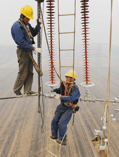 在安徽省淮北市濉溪縣,安徽送變電工程公司的電力工人在40多米的高空進(jìn)行架線作業(yè)。(6月16日攝)新華社發(fā)(宋衛(wèi)星 攝)