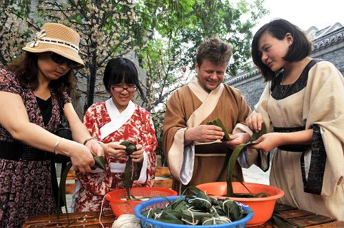 6月22日,入住江蘇揚(yáng)州個(gè)園國(guó)際青年旅社的旅客身穿“漢服”學(xué)包粽子。新華社發(fā)(董輝 攝)