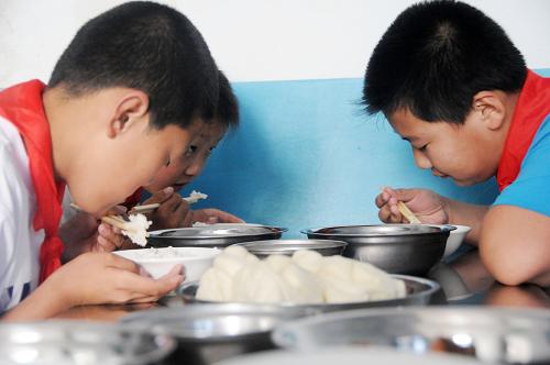 7月3日,黑龍江省綏化市青岡縣連豐鄉(xiāng)中心小學的學生在食堂吃營養(yǎng)午餐。 7月3日,黑龍江省綏化市青岡縣連豐鄉(xiāng)中心小學在學校食堂吃飯的240名同學第一次吃上營養(yǎng)搭配合理、味道可口的菜肴,正式告別了木耳、白菜、土豆、干豆腐、豆芽一鍋燉的“雜拌”菜時代。自此,黑龍江省貧困地區(qū)青岡縣、明水縣具備“希望廚房”設備的農村小學的5000名學生可以在學校吃上放心、營養(yǎng)的午餐了。 2012年6月黑龍江省青少年發(fā)展基金會啟動了“希望廚房”公益項目,該項目通過動員社會各界力量,募集專項公益資金,為黑龍江省農村貧困地區(qū)小學配備現(xiàn)代化廚房設備。在愛心企業(yè)的捐助下,目前已經有31所農村小學即將有自己的廚房。其中青岡縣、明水縣的11所小學設備現(xiàn)已經安裝完畢。 新華社記者 王凱 攝