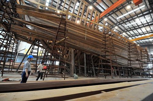 7月3日,明代寶船廠遺址上的復(fù)建廠房內(nèi),寶船復(fù)建施工正在進行中。 近日,南京“鄭和寶船”復(fù)建工程取得重要進展。在位于明代寶船廠遺址上的復(fù)建廠房內(nèi),龐大的寶船主船體結(jié)構(gòu)基本建成,即將轉(zhuǎn)入底板和甲板鋪設(shè)、設(shè)備定貨、桅桿風(fēng)帆設(shè)計及仿古裝修等工程階段。7月11日,南京作為2012中國航海日活動主會場,這艘初顯雛形的“仿明代鄭和寶船”將接受各地來賓的參觀考察。 復(fù)建中的“鄭和寶船”是以各種史料為依據(jù),按等比例、全木質(zhì)結(jié)構(gòu)、可進行遠(yuǎn)洋航行的要求設(shè)計建造的。寶船由造木船世家傳人組成的工匠隊伍、采用傳統(tǒng)的木船建造工藝建造。據(jù)介紹,為適應(yīng)現(xiàn)代航海要求,寶船也將裝備各種現(xiàn)代化的高科技先進設(shè)備。 按復(fù)建計劃,這艘“仿明代鄭和寶船”將于今年底完成主體設(shè)備安裝,2014年下水,在試航成功后,開啟“八下西洋”海上之旅。 新華社記者孫參攝