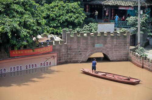 7月6日,在磁器口古鎮(zhèn)老城門——清水門前,一名避險躉船上的工作人員利用小船在半淹沒于水中的城門和躉船之間往返。 當日,嘉陵江今年截至目前最大的洪峰通過重慶主城區(qū),在朝天門匯入長江。洪峰的抵達使流經(jīng)重慶主城區(qū)的嘉陵江水暴漲近3米,嘉陵江畔的千年古鎮(zhèn)磁器口變身“水城”。300余戶磁器口的商家在當?shù)卣M織下有序撤離,一排排明清建筑風格的商鋪浸泡在江水中,只露出青瓦頂,大量避險躉船只能將臨時人行通道直接搭在臨江商鋪的屋頂上。據(jù)設在磁器口的嘉陵江臨時水文監(jiān)測點監(jiān)測顯示,磁器口嘉陵江水位在當日上午11時達到了183.85米,至下午14時開始逐步減退,預計嘉陵江今天至后天水位將可能陡退12.58米。 新華社記者 劉潺 攝