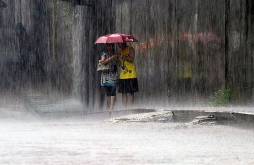 7月13日,武漢市江岸區(qū),兩名行人站在雨中。新華社發(fā)