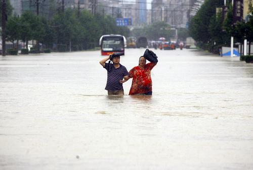 7月13日,行人在武漢積水嚴(yán)重的街道涉水而行。新華社發(fā)
