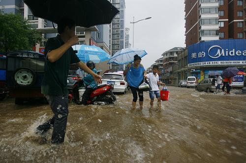 7月13日,行人在武漢積水嚴(yán)重的街道涉水而行。新華社發(fā)