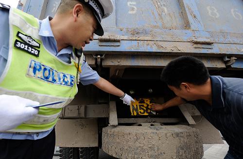 7月16日,重慶市渝中區(qū)交警支隊(duì)民警要求一位駕駛員將字跡不清的號(hào)牌擦拭干凈。新華社記者 李健 攝