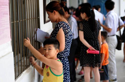 7月17日,在合肥朝霞小學(xué)報名點,一名兒童和家長在辦理報名手續(xù)。 新華社記者 劉軍喜 攝