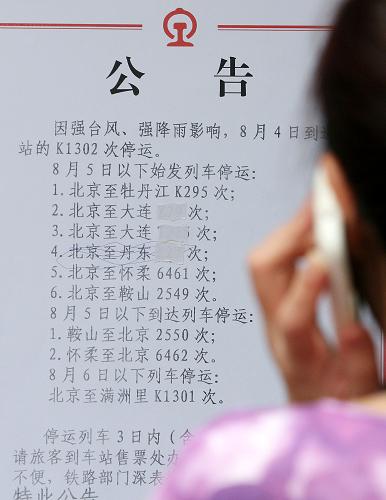 8月5日,旅客在北京站列車停運(yùn)公告前打電話。新華社發(fā)(卓恩森 攝)