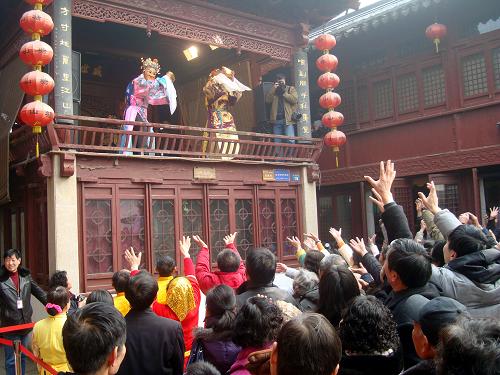 2月7日,裝扮成“財(cái)神”的民俗演員在江蘇蘇州山塘古街古戲臺(tái)上向觀眾散發(fā)“元寶糖”。新華社發(fā)(王建康 攝)