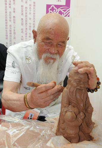 6月10日,在北京中華世紀壇當代藝術中心,81歲的國家級非物質(zhì)文化遺產(chǎn)項目代表性傳承人楊棲鶴在向觀眾展示泥塑雕刻。新華社發(fā)(王振攝)