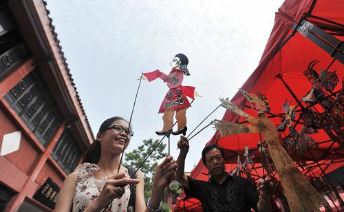 6月11日,皮影民間藝人馬飛(右)向市民展示皮影作品。當(dāng)日是我國(guó)第六個(gè)“文化遺產(chǎn)日”。安徽合肥市邀請(qǐng)多名擁有皮影戲、蛋雕、剪紙等技藝的民間非物質(zhì)文化遺產(chǎn)傳承人在合肥城隍廟進(jìn)行現(xiàn)場(chǎng)技藝表演和創(chuàng)作,號(hào)召市民積極參與非物質(zhì)文化遺產(chǎn)的保護(hù)和傳承。新華社記者 劉軍喜 攝