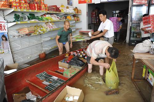 6月20日,蘭溪市女埠鎮(zhèn)一家小超市店內(nèi)進(jìn)水,人們忙著轉(zhuǎn)移物品。新華社發(fā)(梁臻 攝)