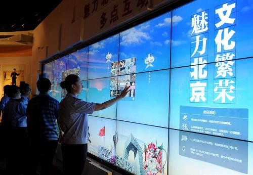 6月26日,觀眾在通過電子觸摸屏了解展出的關(guān)于北京文化遺產(chǎn)的內(nèi)容。新華社記者 羅曉光 攝