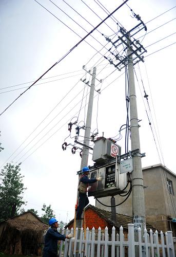 7月20日,五河供電公司工作人員在五河縣沫河口鎮(zhèn)四鋪村檢修低壓配電設(shè)備。新華社記者 許逆之 攝