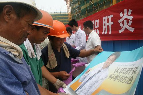 7月28日,在山東濱州市博興縣博昌街道一處建筑工地,農(nóng)民工在觀看“世界肝炎日”公益宣傳畫。新華社發(fā)(陳彬 攝)