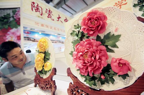 8月12日,在北京國際展覽中心,觀眾在看牡丹花陶瓷花盤。當日,為期3天的2011中國國際婦幼嬰童產(chǎn)業(yè)展覽會暨輕工精品展覽會在北京國際展覽中心開幕,30多個輕工行業(yè)的350多家企業(yè)參展。新華社發(fā)(羅偉 攝)