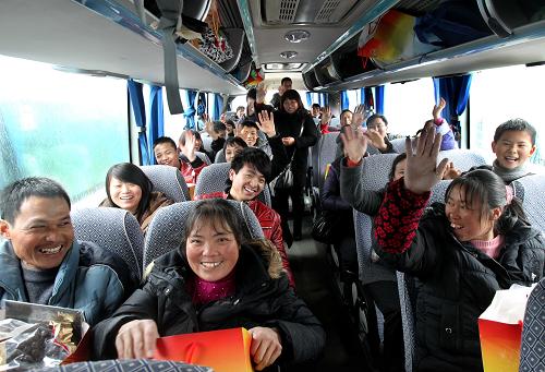 1月15日,在準(zhǔn)備發(fā)往四川成都方向的大巴車上,農(nóng)民工們帶著節(jié)日禮包揮手告別。新華社記者 劉穎 攝