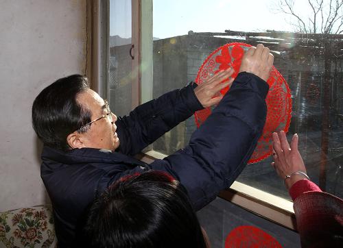 這是胡錦濤在懷柔區(qū)田仙峪村老復員軍人邵起成家中,同他家人一起,把一幅“吉慶有余”的紅色窗花貼到窗上。新華社記者 蘭紅光 攝