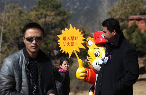1月27日,在云南麗江玉龍雪山風景區(qū),一名工作人員(右一)從“進入景區(qū) 防火第一”的告示牌前走過。云南麗江林火對玉龍雪山景區(qū)沒有造成太大影響,景區(qū)于27日恢復開放迎客。1月26日9時發(fā)生在云南麗江市玉龍縣白沙鄉(xiāng)境內(nèi)的山火明火已基本得到控制,但由于風勢過猛,煙點多且分散,不排除煙點遇風再次形成明火的可能。當?shù)匾呀?jīng)組織了軍警民約3000人開展撲火工作,并對火場進行清理,嚴防明火再燃。新華社發(fā)(梁志強 攝)