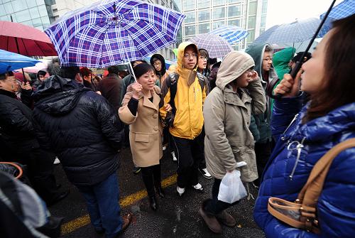 2月12日,在南京廣播電視大學(xué)考點(diǎn),家長(zhǎng)打雨傘接考生出考場(chǎng)。新華社記者 孫參 攝