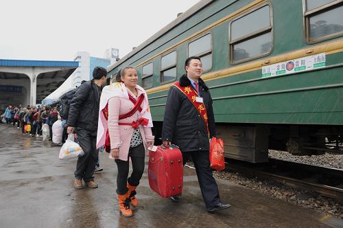 2月18日,貴陽(yáng)火車站工作人員幫助一名婦女拿行李。新華社記者 劉續(xù) 攝