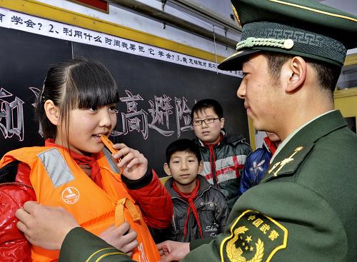 3月23日,唐山市澗河邊防派出所的民警祝亞昭(右)為畢家圈小學(xué)學(xué)生介紹救生衣的正確使用方法。新華社記者 楊世堯 攝