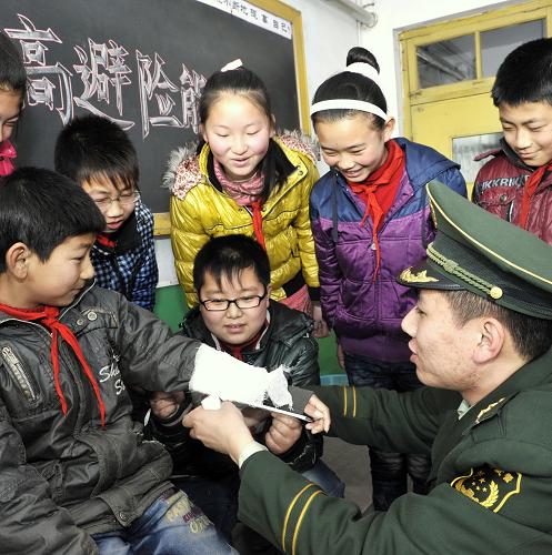 3月23日,唐山市澗河邊防派出所的民警劉育才(右)為畢家圈小學(xué)學(xué)生講解包扎自救知識。新華社記者 楊世堯 攝