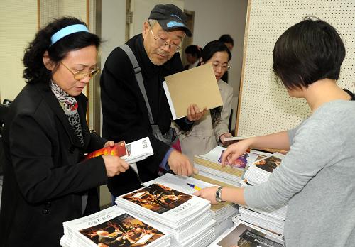 4月8日,在北京東城區(qū)圖書館,前來聽著名作曲家、中央音樂學(xué)院作曲系教授郝維亞講座的社區(qū)居民領(lǐng)取國家大劇院贈閱的藝術(shù)讀物。新華社記者 羅曉光 攝