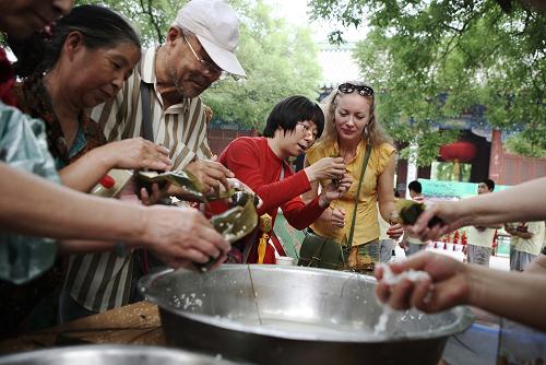 6月21日,一位外國游客(右一)在北京民俗博物館學(xué)習(xí)包粽子。當(dāng)日,“我們的節(jié)日·端午節(jié)系列文化活動”在北京民俗博物館舉行。北京民俗博物館今年的端午活動在保留了原有的包粽子、畫龍舟、斗百草、飲雄黃酒等傳統(tǒng)游園活動特色的基礎(chǔ)上,又增加了端午射柳習(xí)俗等新項目。新華社發(fā)(李方宇攝)