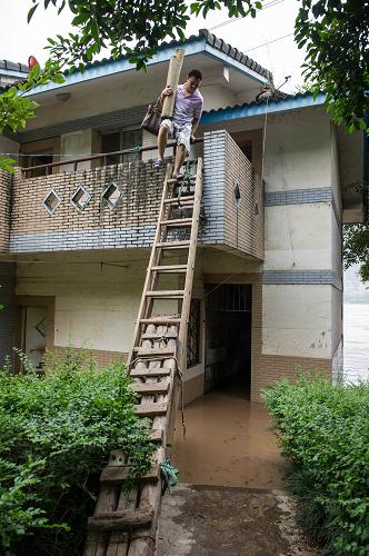 7月23日,由于洪水上漲太快,住在重慶市長(zhǎng)濱路的市民只有搭梯子來(lái)?yè)屵\(yùn)房間里的物品。新華社記者 陳誠(chéng) 攝