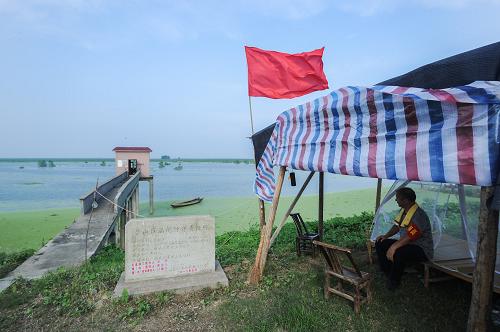 7月22日,在岳陽市君山區(qū)的防洪大堤上,工作人員在臨時防守棚值班。據(jù)君山區(qū)水利局副局長蘆建文介紹,區(qū)里在大堤上設(shè)置了9個值守點,安排人員監(jiān)測大壩有無滲漏等情況,同時各垸水委會按2000米一組,每組3人,對防洪大堤的堤頂、堤身等處實行24小時全方位巡查。新華社記者 白禹 攝