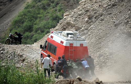 9月9日,一輛救援車輛前往重災(zāi)區(qū)洛澤河鎮(zhèn)的山路倪家?guī)r塌方路段,眾人推車幫助車輛前行。新華社記者秦晴攝