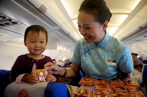 9月30日,在MU2411次航班上,乘務(wù)員(右)為一名小旅客發(fā)放月餅。當(dāng)日,東方航空公司甘肅分公司執(zhí)飛的MU2411次航班上舉辦了主題為“月圓人更圓”萬米高空共度詩意中秋的機(jī)上賽詩會,旅客在萬米高空品詩嘗月餅,體驗了一個不一樣的中秋佳節(jié)。新華社記者 張錳 攝