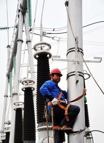 11月29日,一名國家電網(wǎng)湖南省送變電工程公司工程人員在高塔上打雙保險(xiǎn)繩,準(zhǔn)備對(duì)設(shè)備實(shí)施最后階段的施工。新華社記者 趙眾志 攝